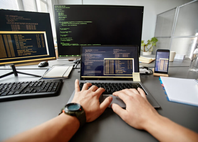 POV of QA engineer typing on keyboard while using computer at workplace in office, copy space